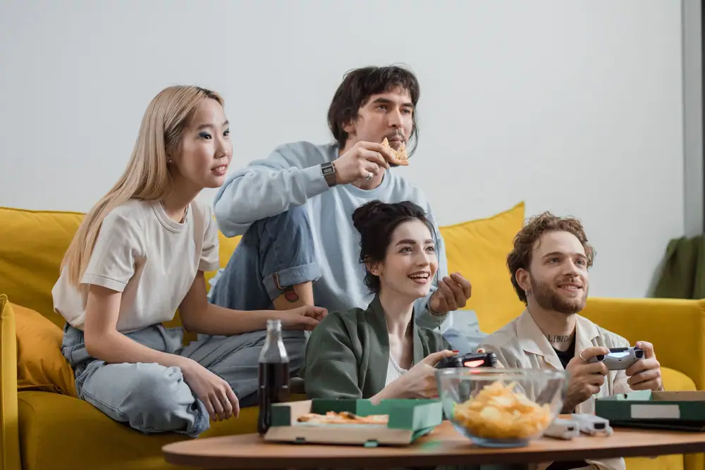 Friends relaxing on a sofa with snacks during a casual game night at home