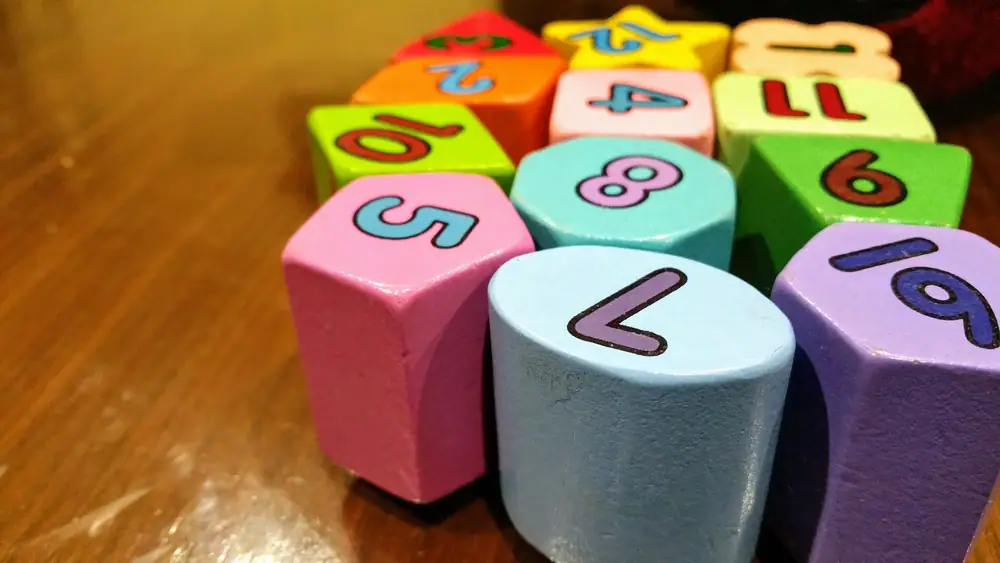 Oversized colorful number dice lined up on a wooden table