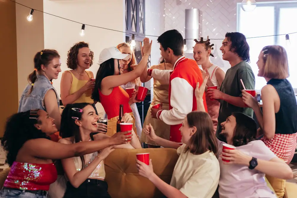 A group of friends laughing and gesturing together at a house party