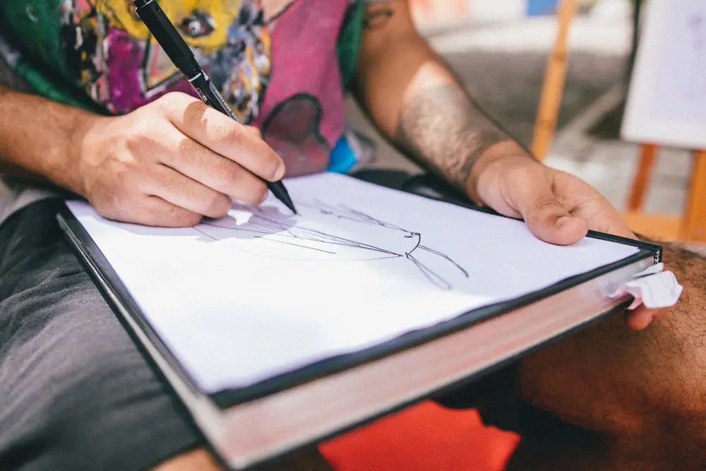 A hand sketching a quick drawing with a pencil on paper