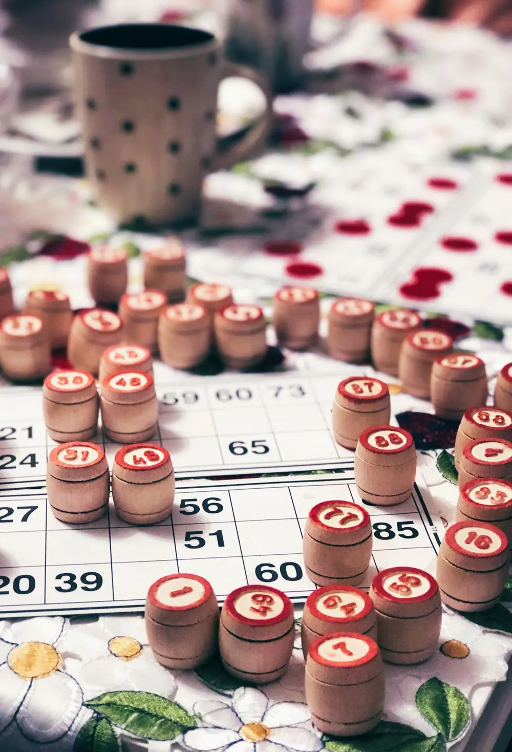 Wooden bingo tokens resting on printed number bingo cards